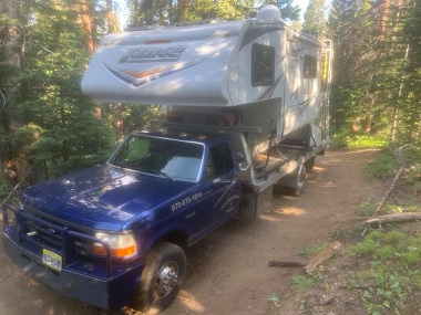 Flatbed tow truck with camper in woods
